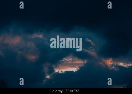 Epic sky at sunset. Dark dramatic sky clouds with orange sunlight holes. Storm weather. Beauty in nature. Twilight, golden hour. Thunderstorm. Evening Stock Photo