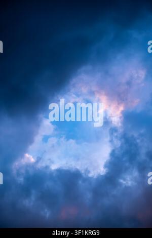 Blue hole in the dark cloudy sky. Storm Clouds. Evening sunset. Rainy and stormy weather. Art wallpaper. Natural landscape. Beauty in nature. After Stock Photo