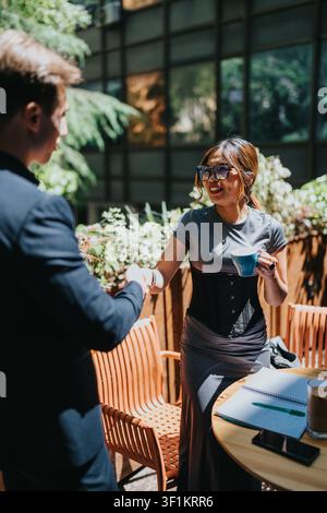Business professionals shaking hands over coffee during an outdoor collaboration meeting at a cafe table Stock Photo