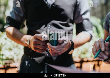 Man holding coffee cup during outdoor business meeting with colleagues taking notes Stock Photo