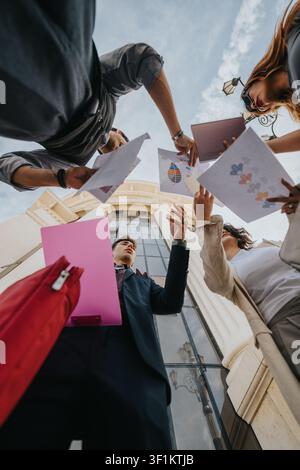 Young professionals and students having an outdoor meeting exchanging documents by a classical building Stock Photo