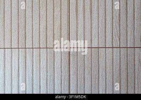 A close-up, straight-on shot of four light-colored wood-effect ceramic wall tiles with a vertical grooved texture, meeting at a central grout line int Stock Photo