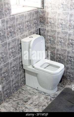 A high-angle, vertical shot of a clean white ceramic flush toilet with its lid open, unlike the previous horizontal image, positioned in a bathroom co Stock Photo