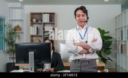 Confident Asian male customer service representative standing in office Stock Photo