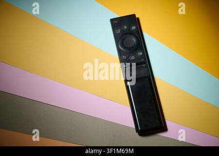 Close up of a television remote control resting on a colourful surface. Watching programs on multimedia television. Stock Photo