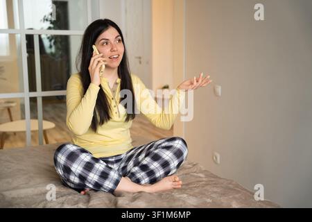 Young woman in casual home setting having a phone conversation with expressive gestures. Remote consultation customer support and emotional communicat Stock Photo