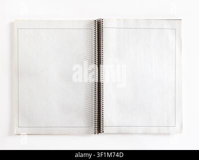 Top view of an open blank spiral notebook with thin black printed borders on white paper sheets isolated on white background. Stock Photo