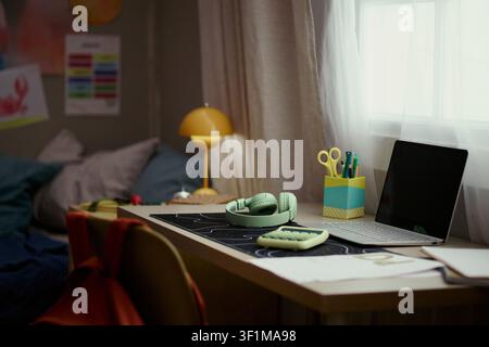 Wide shot of student workspace showing laptop, headphones, calculator, notebooks, supporting online learning and homework planning. Ideal for education, edtech, study campaign use Stock Photo