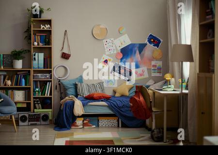 Wide angle shot of child bedroom featuring study desk, bed, bookshelves, backpack, creative drawings, supporting home learning, parenting, back to school marketing Stock Photo