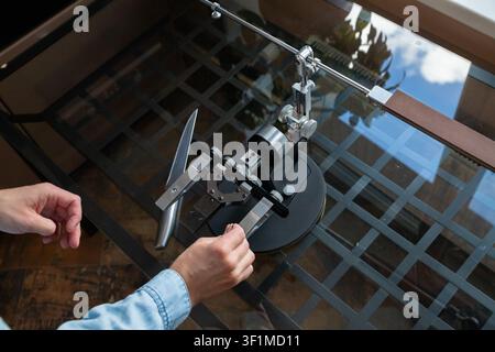 Man sharpening kitchen knife with professional manual guided sharpening system. Maintenance tool for edge precision. Culinary equipment, home hobby, c Stock Photo