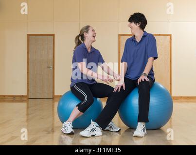Two happy women sitting on gym balls chatting Stock Photo