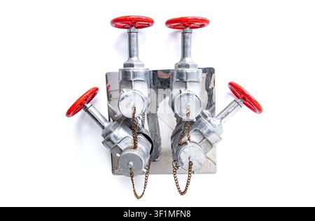Industrial fire department connection with red valve wheels on a metal plate isolated on white background Stock Photo