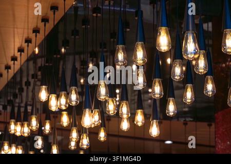 Lots of decorative soft light bulbs hanging from the ceiling in a dark room. Stock Photo