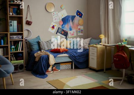 Wide shot of teenager bedroom displaying study desk, bed, backpack, creative drawings and school supplies, suggesting student routine and youth lifestyle. Useful for education or parenting campaigns Stock Photo