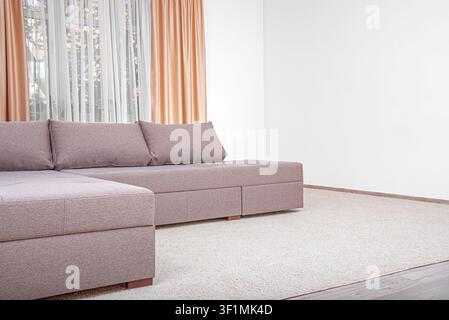 A modern fabric sectional sofa stands in a bright room. Stock Photo