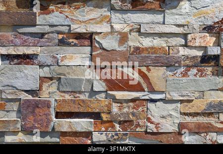 Stacked stone coating wall for indoor or outdoor. Multicolored natural rock assembled with a mix of slate and quartzite. Background and texture Stock Photo
