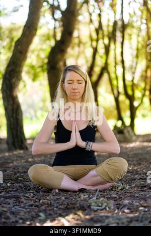 Woman practicing meditation and yoga in peaceful natural park setting Stock Photo