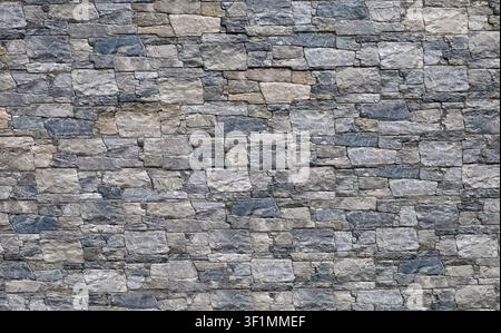Stoneware paneling wall with old stonewall effect. Colors are gray, black, brown and white. External wall covering, background and texture. Stock Photo