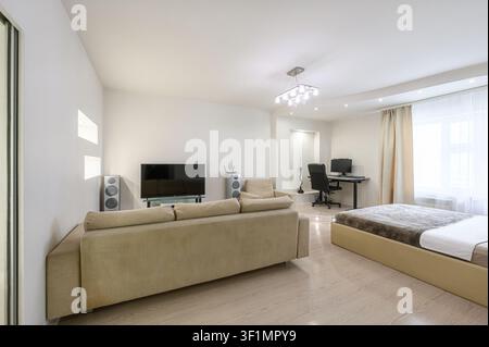 modern apartment interior featuring a sofa, bed, workspace, TV, and minimalist decor in a bright, open layout Stock Photo