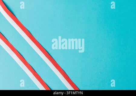 Two parallel diagonal red and white striped ribbons on a clean turquoise background. Excellent minimalist template for Indonesian independence day, cards, announcements, and advertisements. High Quality Photo Stock Photo