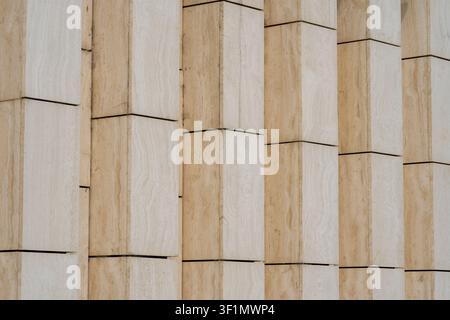 Close-up of a modern building facade showing repeating vertical stone panels and clean geometric lines, highlighting architectural texture, rhythm, an Stock Photo