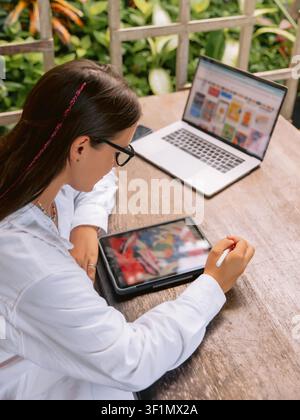Woman working with laptop and tablet in outdoor workspace Stock Photo