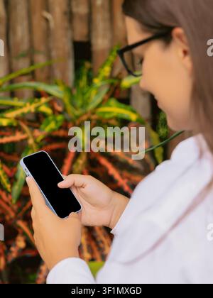 Woman using smartphone outdoors in natural setting Stock Photo