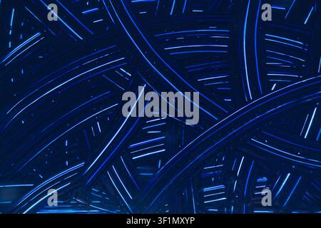 Abstract background of glowing blue neon lines and light streaks crossing a dark surface, with small spark-like particles, creating a futuristic tech Stock Photo