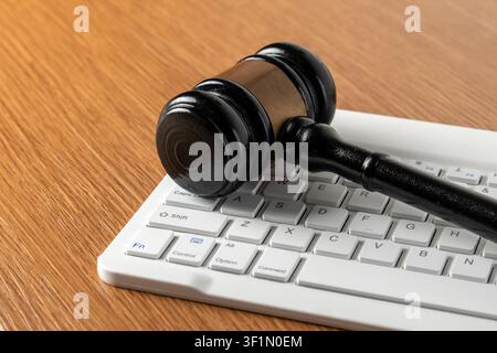 Wooden judge gavel on a white computer keyboard. Cyber law, digital justice, online crime, internet regulations concept. Stock Photo