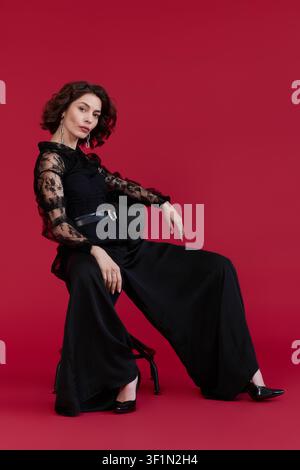 A young brunette woman showcases her style in a chic black lace blouse while posing Stock Photo