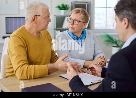 Senior couple meeting financial advisor to review investments and sign agreement Stock Photo