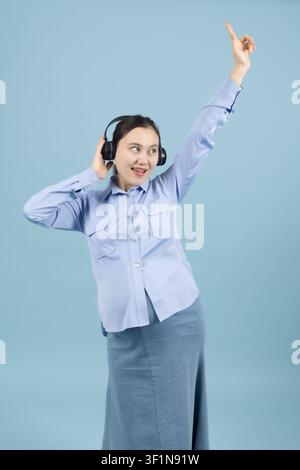 Joyful pregnant woman wearing headphones and dancing to music Stock Photo