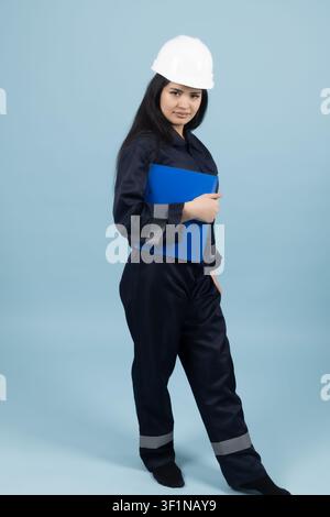 Professional female builder wearing hard hat and holding folder in the studio Stock Photo