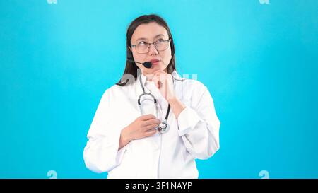 Female doctor wearing stethoscope and glasses looking up thoughtfully in the ... Stock Photo