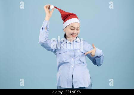 Happy young woman wearing santa hat and pointing fingers at herself in the st... Stock Photo