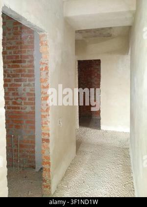 A view down a hallway in an apartment undergoing major renovation, showing unfinished walls and floors Stock Photo
