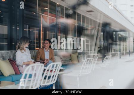Two colleagues having a casual business meeting at an outdoor cafe discussing remote work Stock Photo