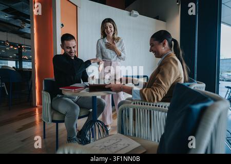 Colleagues celebrating successful remote work meeting in a modern coworking lounge Stock Photo