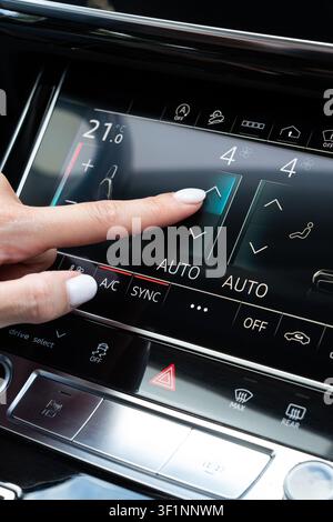 Female hand touching airflow intensity arrow on digital dashboard screen inside vehicle. Close-up viewpoint on dashboard console panel regulating vent Stock Photo