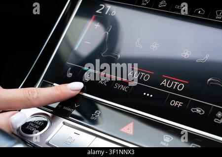 Female hand touching seat ventilation icon on digital climate control panel inside premium auto. Close-up viewpoint on dashboard console activating ve Stock Photo