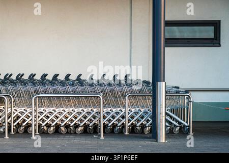 Rows of shopping carts neatly parked outside a supermarket entrance, prepared for customers and everyday grocery shopping Stock Photo