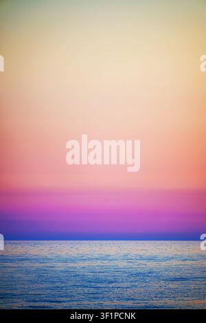 Colorful ocean sunset with calm sea horizon and pastel gradient sky, minimalist seascape with copy space. Stock Photo