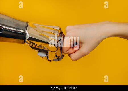 Human and robotic hands joining in a fist bump, representing innovative collaboration, the merging of human and artificial intelligence, and cutting edge technological partnership Stock Photo