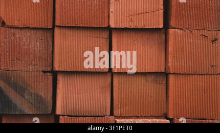 A close up view of stacked red clay bricks highlighting their textured, ridged surfaces Stock Photo
