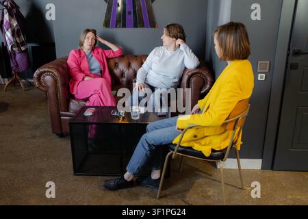 Two women having thoughtful conversation in cafe, sitting in modern chairs by window. Cafe, thoughtful, conversation, window, modern. Stock Photo