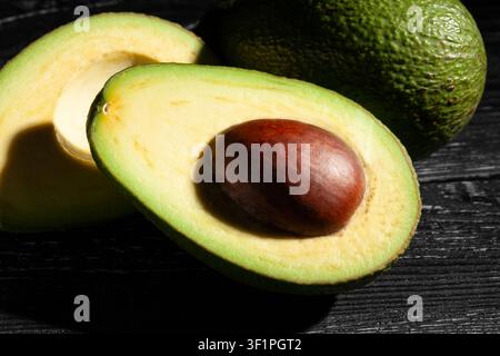 sliced avocado on black wood background Stock Photo
