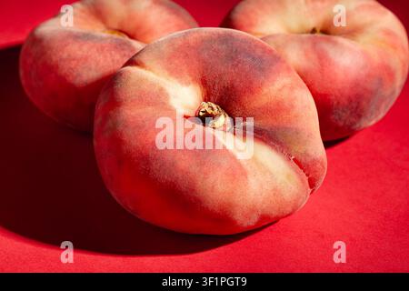 flat peaches on red background Stock Photo