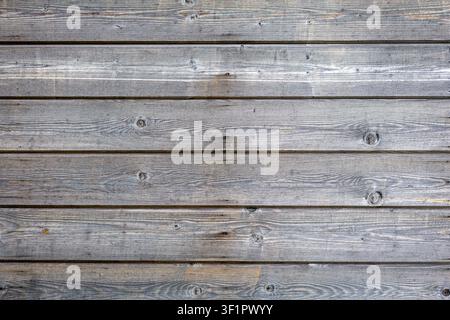 Weathered Gray Wooden Plank Wall Texture. Weathered gray wooden planks form a rustic horizontal wall with visible grain, knots, seams, and small nails Stock Photo