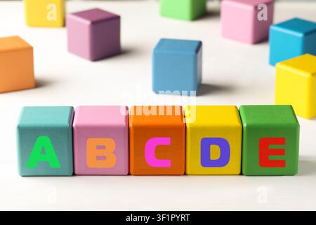 Learning alphabet. Wooden cubes with letters on white table Stock Photo