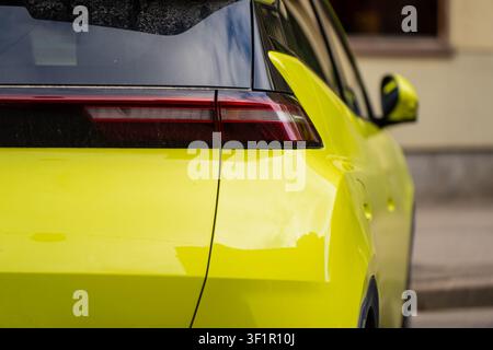 modern rear LED taillight and sleek body panels of a contemporary bright yellow hatchback car in an urban setting Stock Photo